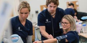 A UBCO Nursing student placing a stethoscope on their classmate's arm